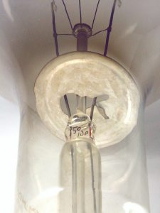 Pie y deflector trmico construido en metal, sostenido por una lmina metlica soldada a uno de los alambres de acometida.